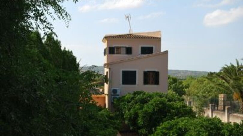 Außenansicht der Finca in Manacor, umgeben von üppigem Grün und Palmen, mit mediterraner Architektur.