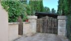 Einfahrtstor aus Holz mit Natursteinmauer und üppigem Grün der Finca in Manacor