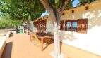 Sunny terrace with wooden furniture and shade-providing trees of a well-maintained Mallorca finca in Son Carrió