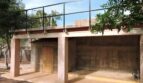 Überdachter Carport mit Dachterrasse und schwarzem Metallgeländer, umgeben von Bäumen der Finca in Manacor