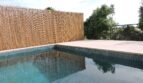 Pool der Finca in Manacor mit Mosaikfliesen, hellem Steinbelag und Sichtschutz aus Bambus