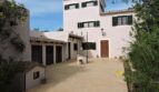 Außenansicht der Finca in Manacor mit weißer Fassade, grünen Fensterläden und gepflastertem Innenhof