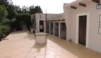 Sonniger Innenhof der Finca Manacor mit Steinboden, dekorativem Brunnen und weißen Gebäuden mit Holzbalken.