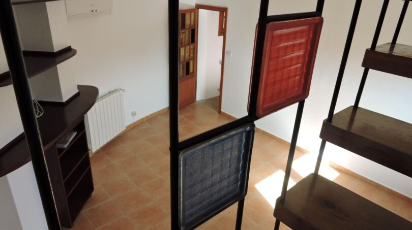 Treppenaufgang mit Metallgeländer und Glaspartition, Blick auf Wohnbereich mit Terrakottaboden und Heizkörper der Finca Manacor