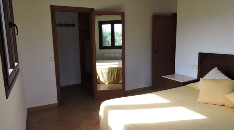 Helles Schlafzimmer der Finca Manacor mit Doppelbett, Wandspiegel, Einbauschrank und Terrakottaboden