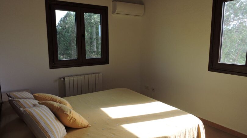 Helles Schlafzimmer der Finca Manacor mit Doppelbett, Klimaanlage, Heizkörper und Blick ins Grüne