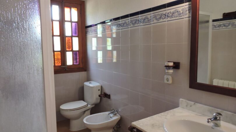 Badezimmer der Finca Manacor mit Toilette, Bidet, Marmor-Waschbecken und buntem Buntglasfenster