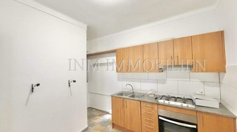 Kitchen with wooden cabinets, built-in oven, double sink and tile backsplash in apartment needing renovation, Playa de Palma