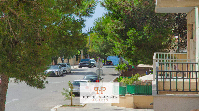 Calle tranquila en Porto Cristo con vistas al mar, pinos e instalación residencial bien cuidada cerca de la playa.