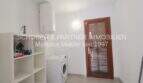 Utility room of the Mallorca finca with washing machine, boiler, shelf and wooden door to the outdoor area.