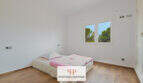 Helles Schlafzimmer der Finca Santa Maria mit Holzboden, Doppelbett und Blick auf grüne Bäume.