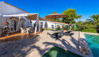 Sunny pool terrace of the sea view villa in Cala Murada with sun loungers, parasol and Mediterranean garden