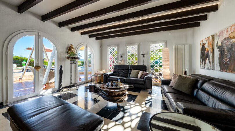 Elegant living room of the sea view villa in Cala Murada with leather furnishings, wooden beam ceiling and terrace access