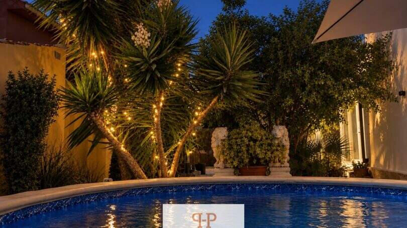 Beleuchteter Pool bei Nacht mit Palmen und Steinlöwen-Skulpturen, Haus in Cala Murada