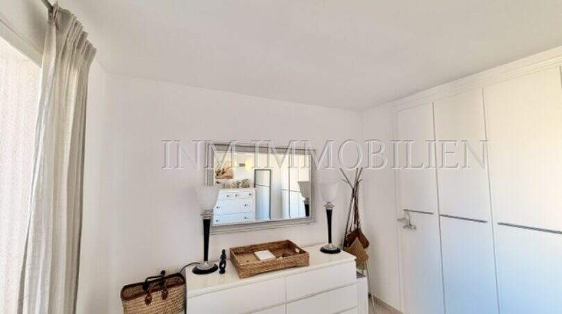 Helles Schlafzimmer mit weißer Kommode, Spiegel und Einbauschrank in Wohnung in Palmanova