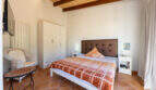Bright bedroom of the sea view villa in Cala Murada with wooden beam ceiling, double bed and terracotta floor.