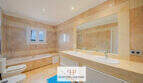 Helles Badezimmer der Finca Santa Maria mit Doppelwaschbecken, Badewanne und Marmorfliesen in Beige.