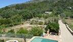 Außenbereich des Landhauses in Llucmajor mit Pool, gepflegtem Garten und Blick auf bewaldete Hügel.