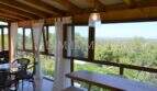 Veranda mit Holzbalkendecke, weißen Vorhängen und Panoramablick über Llucmajors Landschaft bis zum Meer.