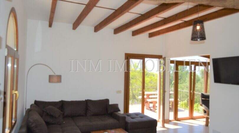 Helles Wohnzimmer mit Holzbalkendecke, Sofa und Terrassenzugang im Landhaus Llucmajor
