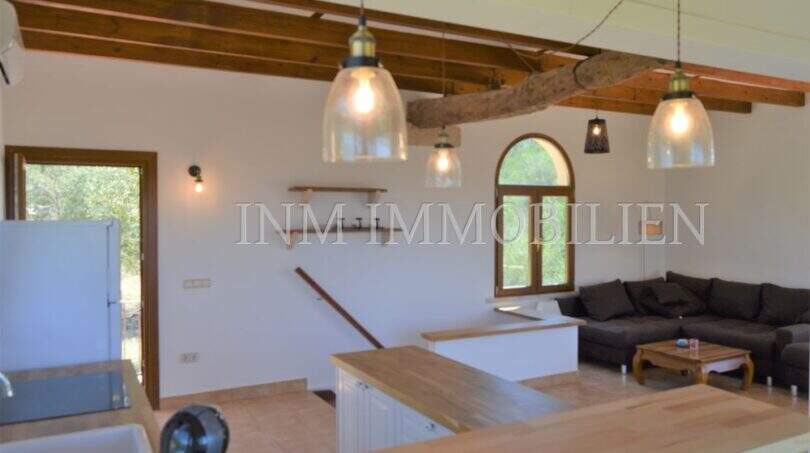 Offener Wohn-Küchenbereich mit Holzbalkendecke, Pendelleuchten und Bogenfenster im Landhaus Llucmajor