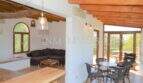 Offener Wohn-Essbereich mit Holzbalkendecke, dunklem Sofa und Terrassenzugang im Landhaus Llucmajor