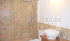 Badezimmer des Landhauses in Llucmajor mit Glasdusche, Aufsatzwaschbecken und beigen Fliesen.
