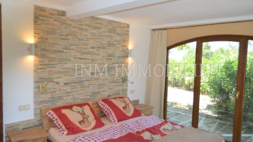 Schlafzimmer mit Steinwand, Doppelbett und Terrassenzugang zum Garten im Landhaus Llucmajor