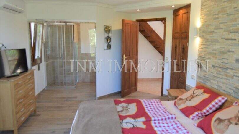 Schlafzimmer mit Doppelbett, Duschkabine, TV und Steinwand im Landhaus Llucmajor