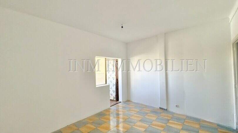 Empty living space with checkerboard tile floor in apartment needing renovation at Playa de Palma