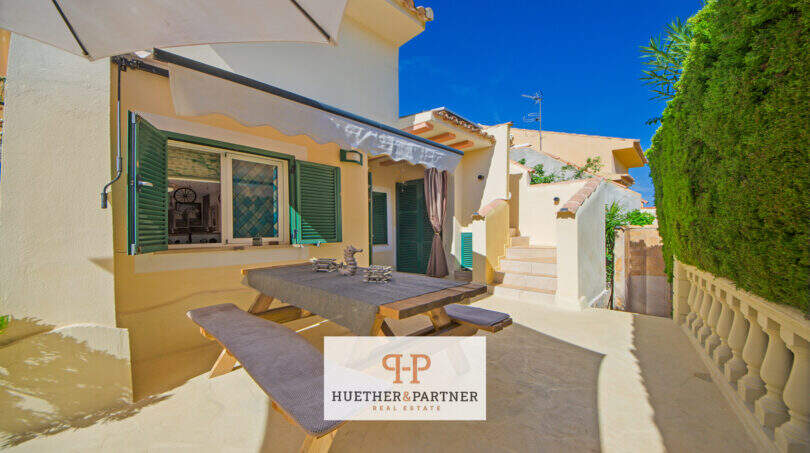 Sonnige Terrasse mit Esstisch, grünen Fensterläden und Markise in Cala Murada