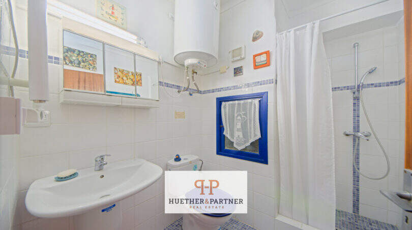 Luminoso baño con ducha, lavabo y ventana en apartamento vacacional cerca de la playa Porto Cristo, Mallorca.