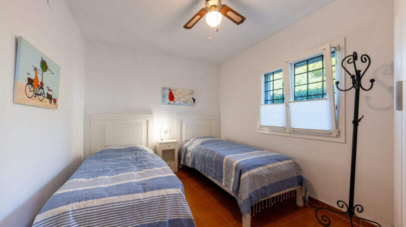 Bright bedroom of the villa in Cala Murada with two single beds, terracotta floor and ceiling fan.