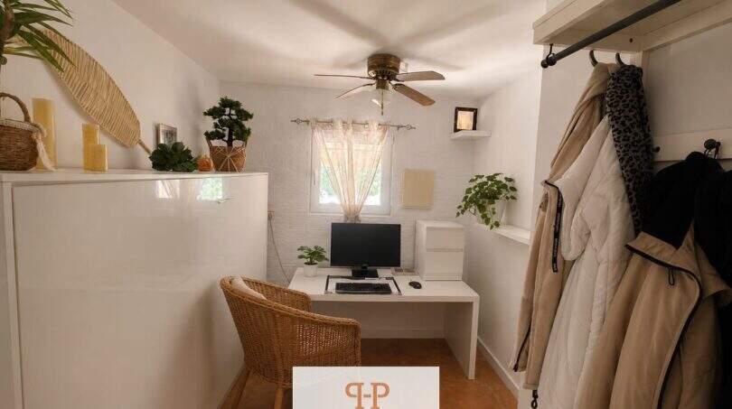 Helles Arbeitszimmer mit weißem Schreibtisch, PC, Korbstuhl, Deckenventilator und Garderobe im Strandhaus Porto Cristo Novo
