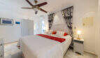 Helles Schlafzimmer der Poolvilla in Cala Murada mit Doppelbett, Deckenventilator und elegantem weißen Ambiente.