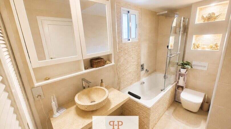 Elegantes Badezimmer mit Naturstein-Waschbecken, Badewanne und Dusche im Ferienhaus nahe Porto Cristo Novo