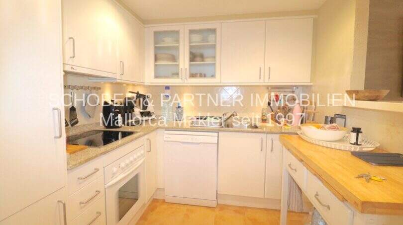 Cocina integrada blanca moderna con encimera de granito, lavavajillas y horno en el apartamento de 4 habitaciones, Cala Millor