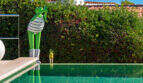 Infinity pool with mirrored water surface and decorative frog sculptures, surrounded by lush hedge at Villa Cala Murada
