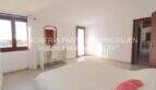 Bright bedroom of the Mallorca finca with white walls, wooden windows, dressing table and pink pillows on the bed.