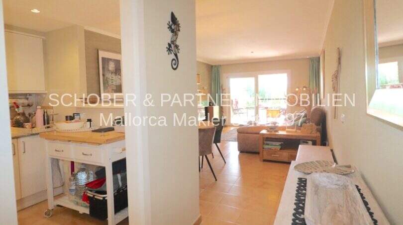 Área de estar abierta con cocina, mesa de comedor y salón luminoso con acceso a terraza en Cala Millor