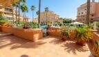 Sonnige Terrasse mit Poolzugang, Palmen und mediterranen Wohnanlagen in Sa Coma, Mallorca.