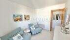 Helles Wohnzimmer mit türkisfarbenem Sofa, Sessel und dekorativen Gemälden in Wohnung in Palmanova