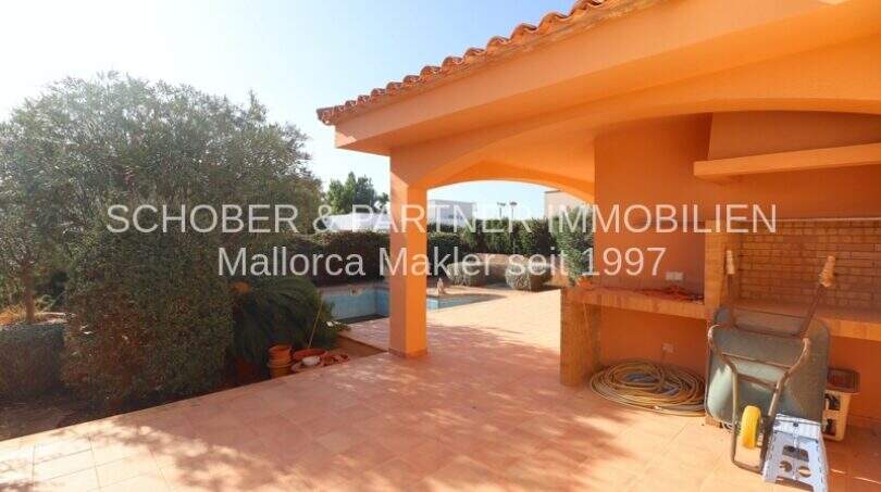 Überdachte Terrasse mit Grillbereich und Blick auf den Pool des Chalets in Sa Coma, Mallorca.
