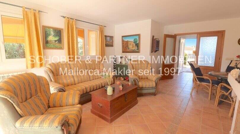 Helles Wohnzimmer mit gestreiften Sofas, Terrakottaboden und Zugang zur Terrasse im Chalet Sa Coma