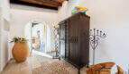 Entrance area of the sea view villa in Cala Murada with wooden beam ceiling, dark wooden cabinet and barrel arch.