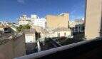 Balcony view of courtyard and surrounding buildings in Ses Cadenes, Palma de Mallorca, with blue sky.