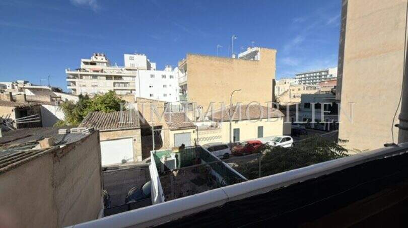 Balcony view of courtyard and surrounding buildings in Ses Cadenes, Palma de Mallorca, with blue sky.