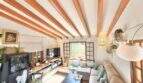 Salón con techo de vigas de madera, conjunto de sofá beige y área de TV en casa mediterránea en Sa Ràpita