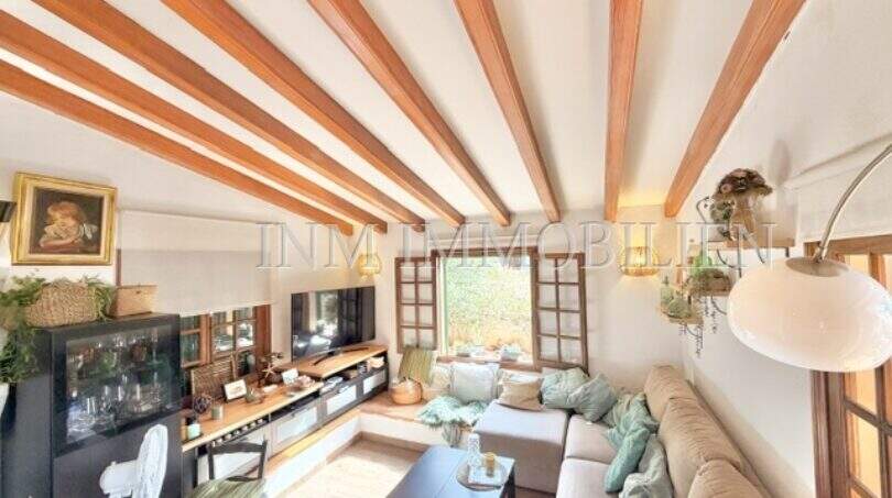 Salón con techo de vigas de madera, conjunto de sofá beige y área de TV en casa mediterránea en Sa Ràpita