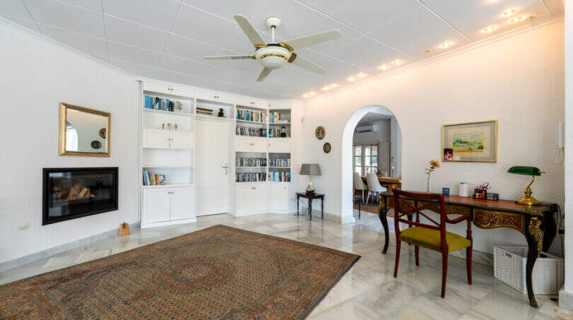 Elegantes Wohnzimmer mit Marmorboden, Kamin, Bücherregal und Schreibtisch in Villa Cala Murada